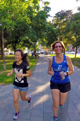 Two runners headed back to the meeting point through a downtown park in the summer evening