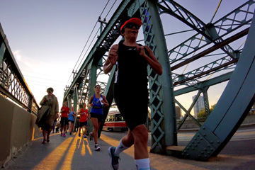 Four runners cross the Queen Street bridge over the Don River at sunset