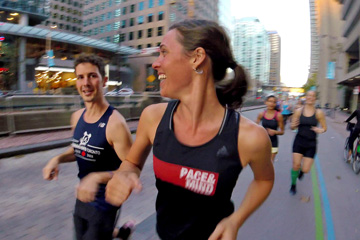 Close shot of two runners laughing while moving fast down Queen's Quay