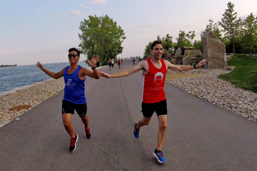 Two runners, arms outstretched, headed north on the Trillium Park waterfront path